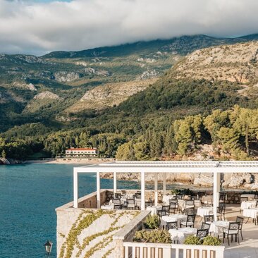 Arva Terrace at Aman Sveti Stefan overlooks turquoise Adriatic waters and forested Montenegro coastline.