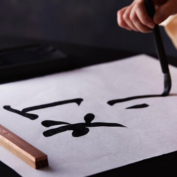 Mani che praticano la calligrafia giapponese ad Amanemu.