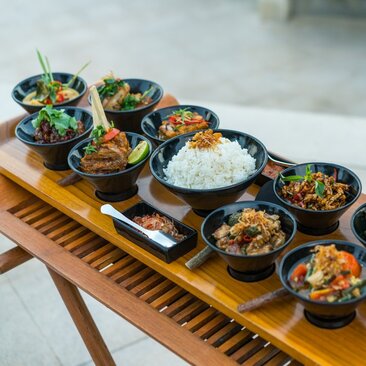 Rijsttafel menu display at Amankila resort, Indonesia, with traditional small bowls of colourful curries and rice arranged on a wooden board.