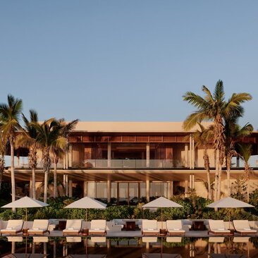 Casa Grande at Amanvari, a terracotta-coloured colonial building with palm trees and poolside loungers at sunset.