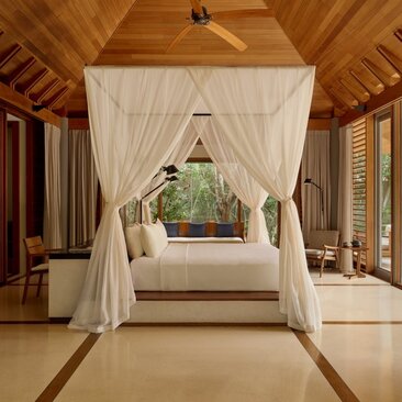 Alcove pool pavilion principal bedroom at Amanyara resort with four-poster bed and draped curtains overlooking tropical gardens, Turks and Caicos.