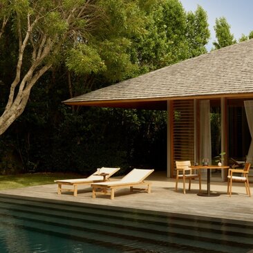 Alcove pool pavilion with sundeck at Amanyara resort, Turks and Caicos, featuring wooden loungers and dining chairs beside a private pool.