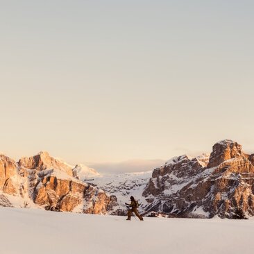 Skiers traversing snow-covered Alpine peaks at Aman Rosa Alpina in Italy during winter.