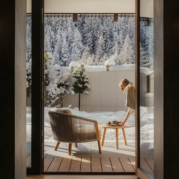 Zen garden view through open doorway at Aman Rosa Alpina, featuring a soaking tub and wooden chair.