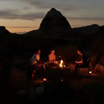 Guests gather around a crackling fire pit at Amangiri as the desert sky darkens at dusk.