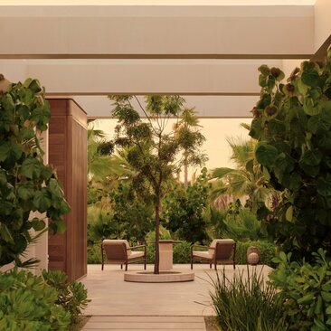 Wooden deck framed by lush greenery leading to an estuary casita at Amanvari, Mexico, with wicker seating visible beyond.