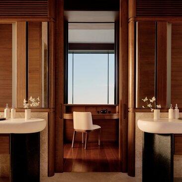 Bathroom at Amanvari with dual wooden vanities, seated mirror area, and desert views through central window.