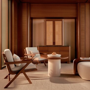 Amanvari Casita living area with warm wood panelling, mid-century chair, and cylindrical stone table.