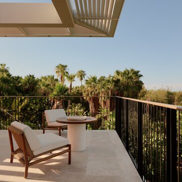 Terrace at Horizon Casita with views across Amanvari's gardens towards mountains, wooden chair in foreground.