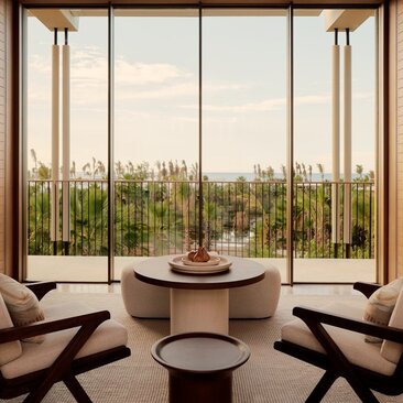 Amanvari casita living area with floor-to-ceiling windows overlooking Mexican landscape and modern seating.
