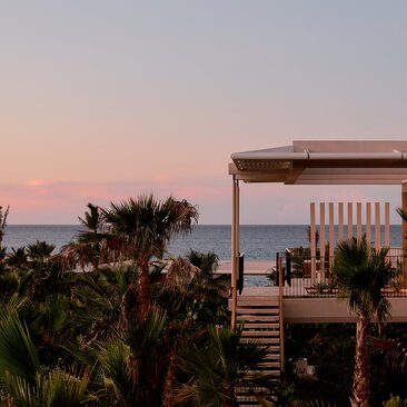 Horizon Casita at Amanvari with ocean view at dusk, framed by palm trees.
