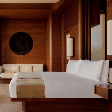 Amanvari Casita bedroom with wooden walls, principal bed with white linens, and circular wall feature.