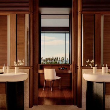 Bathroom at Amanvari with dual vanities, wooden cabinetry and city views through central window.