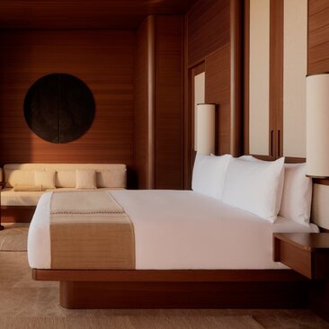 Amanvari bedroom with warm terracotta walls, wooden bed frame, and circular wall art.