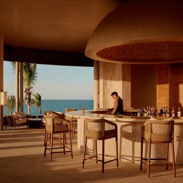 The Lounge Bar at Amanvari overlooks the Mexican coast, with wooden bar seating and warm architectural curves.