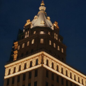 Gilded Art Deco tower of Aman New York illuminated against twilight sky.