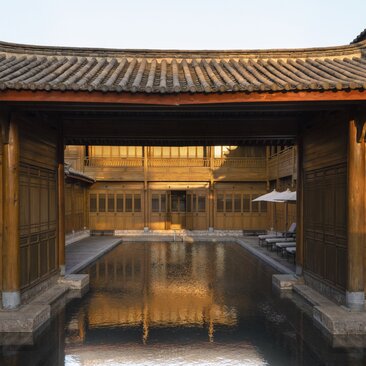 Courtyard at Amandayan with traditional Chinese architecture and golden-lit wooden buildings at dusk.