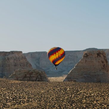 Pallone aerostatico che galleggia sopra il deserto rosso ad Amangiri resort, circondato da formazioni rocciose.