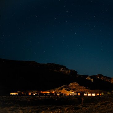 Amangiri resort illuminated at night beneath a star-filled sky in the Utah desert.