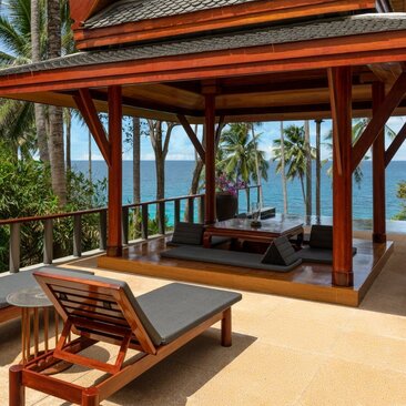 Ocean-facing pool pavilion at Amanpuri, Thailand, with wooden lounger and sea views.