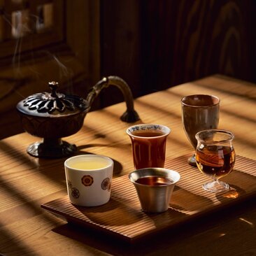 Sunset tea ritual at Amanyangyun, with ceramic vessels and amber-hued tea arranged on wooden table in golden light.