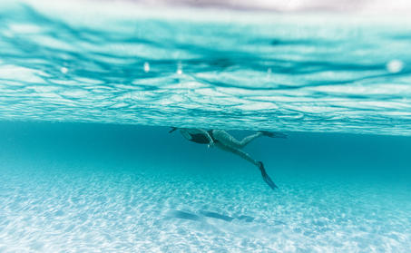 安缦涯澜度假村清澈蔚蓝的海水中，一位游客在浅滩处游泳。