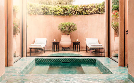 Plunge pool at Amanjena resort with symmetrical seating and potted plants.