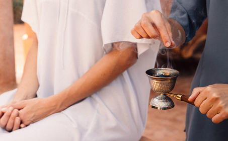 Therapist administering wellness treatment to guest's arm at Amanjena resort.