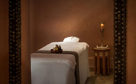 Serene spa treatment room at Amanjena resort with massage bed, soft lighting, and Moroccan-inspired décor.