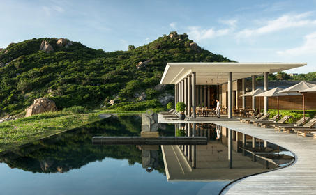 安缦诺怡度假村的餐饮场所，木质建筑映照在平静池水中，周围绿树环抱。