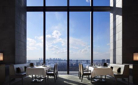 安缦东京餐厅内，大窗户俯瞰东京城市景观，简约餐桌静待宾客。