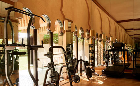 Wellness centre at Amanjena resort with bicycles and fitness equipment displayed along a warm-toned corridor.