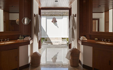 安缦黛宁度假村双卧套房浴室，通过开放式门廊眺望游泳池。