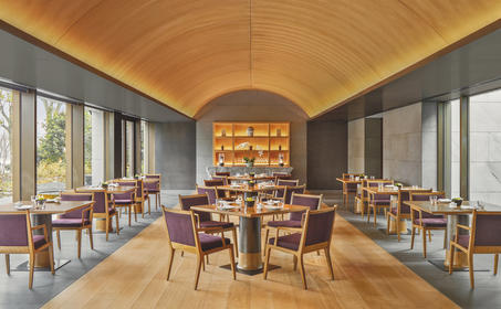 养云安缦度假村主餐厅,木质拱顶天花板下摆放餐桌和座椅。