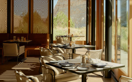 Camp Sarika restaurant at Amangiri with dining table and desert views through large windows.