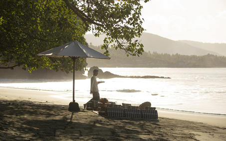 Beachside picnic setup at Amankila with umbrella and seating overlooking calm waters in Bali.