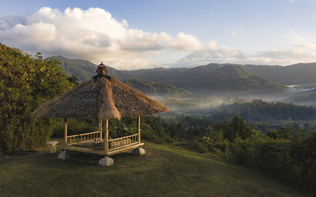 Wooden pavilion at Tamansari breakfast venue overlooking verdant valley and distant mountains at Amankila, Bali.