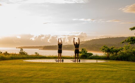 Outdoor fitness structure on manicured lawn at Amanera, Dominican Republic, with river and mountains beyond at dusk.