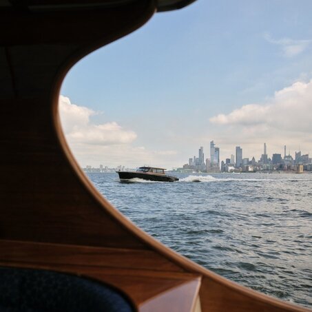 Wooden boat interior framing Manhattan skyline across the water at Aman New York.