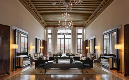 The Drawing Room at Aman Venice, featuring high ceilings, chandeliers, and symmetrical seating arrangements.