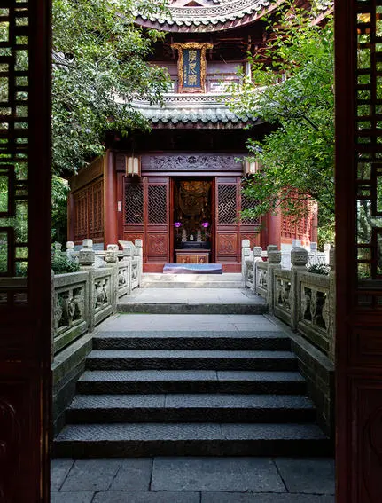 Stone steps lead through a red wooden doorway framed by ivy-covered walls at Amanfayun.