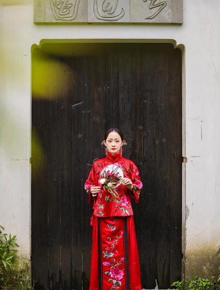 法云安缦度假村，一位身穿传统红色服装的女性站在深色木门前。