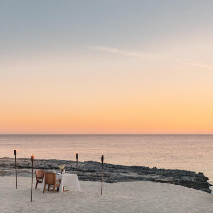 Sunset view over a serene beach with wooden loungers at Amanyara resort.