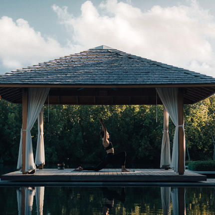 Pavilion with peaked roof reflected in still water at Amanyara resort.