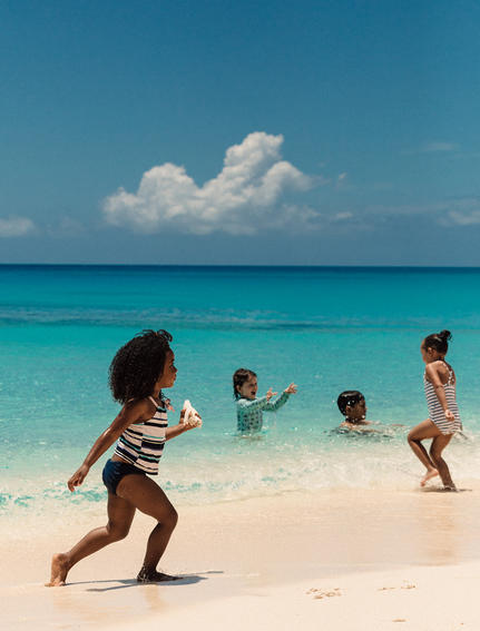 Enfants jouant dans les eaux turquoise d'Amanyara, resort aux Turques-et-Caïques.