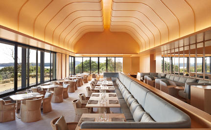 Dining venue at Amanemu resort with wooden barrel-vaulted ceiling and expansive windows overlooking the coastline.