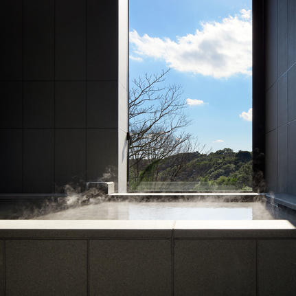 Amanemu resort's minimalist bathroom window framing bare tree branches and blue sky.