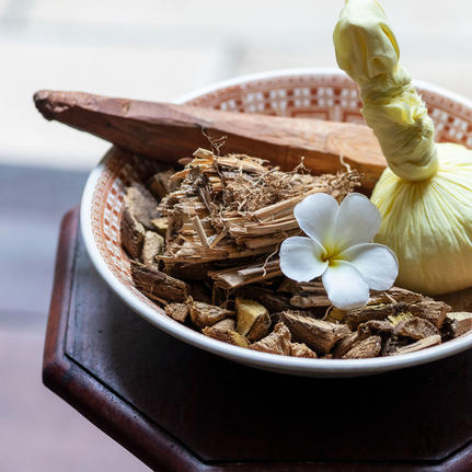 Wooden ornaments and a small white flower arranged in a shallow bowl at Amangalla.