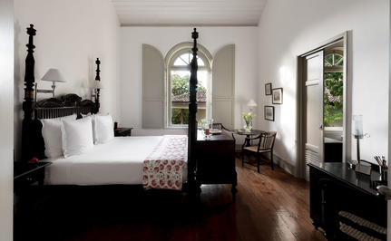 Principal bedroom at Amangalla with four-poster bed and arched doorways opening to gardens.