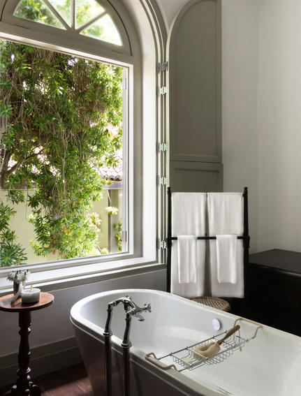 Arched window with garden views beside a bathroom sink at Amangalla.